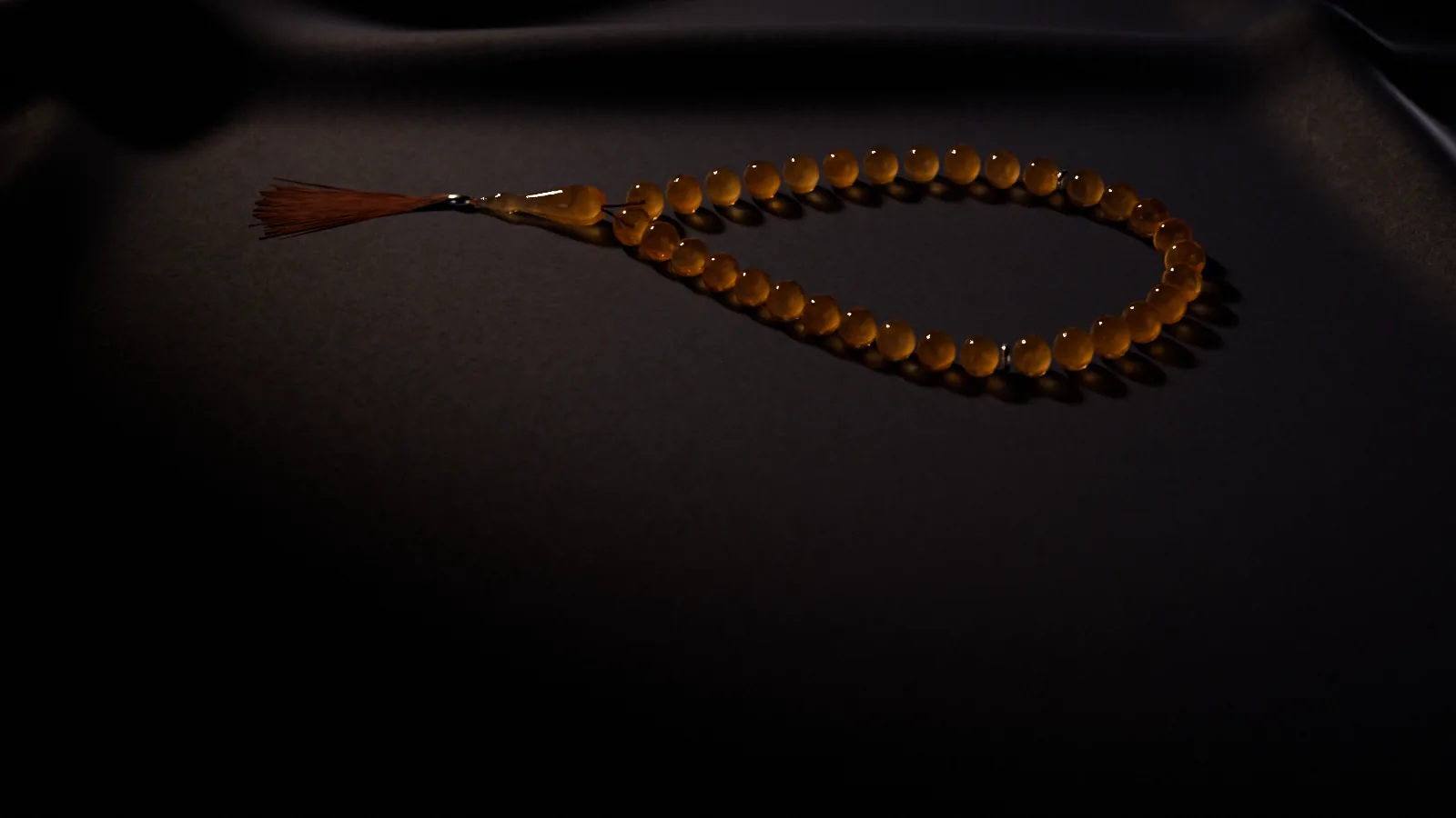 Koyu kumaş üzerinde kehribar tespih ve püskülü